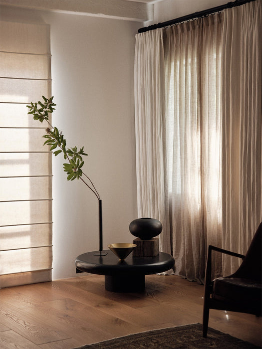 A black coffee table displaying the gold and black Taper Bowl, the black Surround Vase, and the tall black Stance Vase.