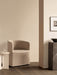 The Tearoom Club Chair in a sandy loose cover, placed next to a white Androgyne Side Table and a tall, dark marble Plinth.