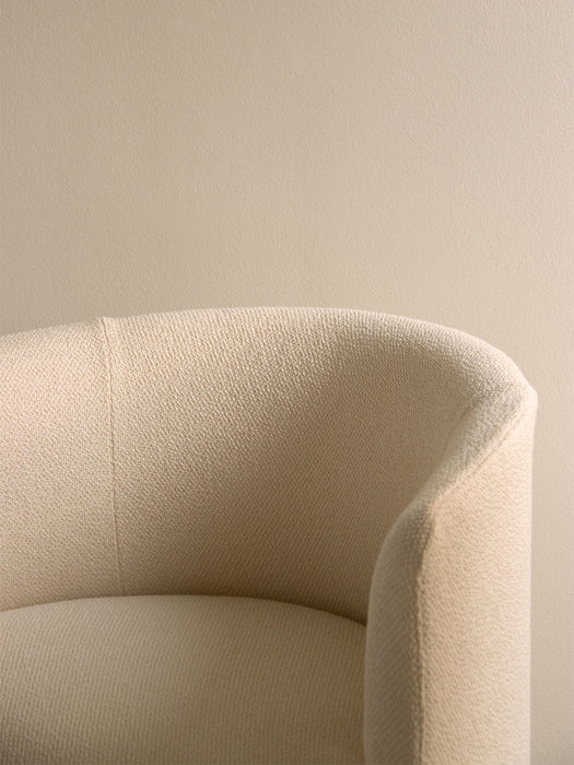 A close-up of the Tearoom Club Chair, showing the texture and curve of its off-white loose cover against a beige wall.