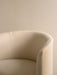 A close-up of the Tearoom Club Chair, showing the texture and curve of its off-white loose cover against a beige wall.