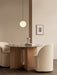 Two cream Tearoom Club Chairs at the Androgyne Dining Table. A TR Bulb Pendant hangs above the grey marble tabletop.