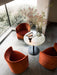 Three rust-coloured velvet Tearoom Club Chairs around a marble cafe table by a large window overlooking a garden.