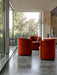 Three rust-coloured velvet Tearoom Club Chairs in a minimalist room with floor-to-ceiling windows overlooking a lush garden.