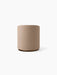 Front view of the cylindrical Tearoom pouf, upholstered in textured beige Logan Flint fabric, with a dark recessed base.