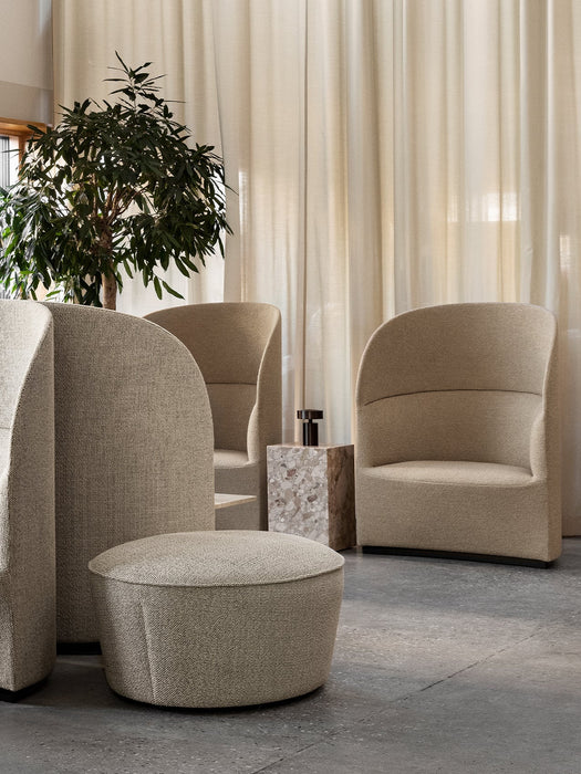 A lounge setting with several sand-coloured Tearoom Lounge Chairs and a Cairn Pouf by a marble Plinth Cubic side table.