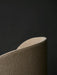 A close-up of the Tearoom Lounge Chair, High Back, showing the textured light brown upholstery on its curved top corner.