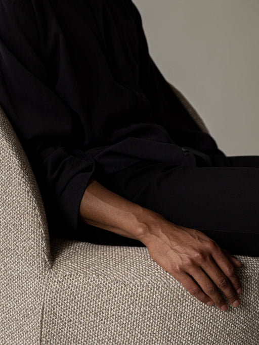 Close-up of the Tearoom Lounge Chair showing the detailed texture of the fabric upholstery with a person's arm resting on it.