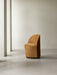 The Tearoom Club Chair, Swivel w/ Return, in mustard-coloured upholstery, sits in a minimalist space with concrete floors.