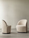 Two cream-coloured Tearoom Club Chairs with dark swivel bases in a minimalist room with concrete floors and a beige wall.