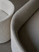 A close-up image of the Tearoom Sofa, showcasing the textured light fabric and the elegant, curved lines of its backrest.
