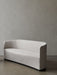 A three-quarter view of the Tearoom Sofa in a cream fabric, featuring a sculptural curved back and a recessed black base.