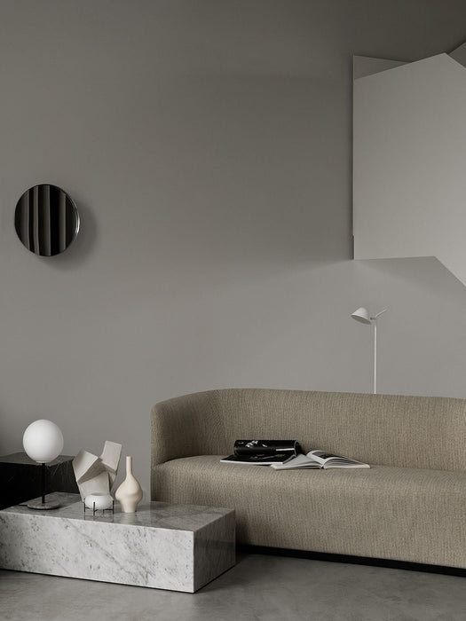 A beige Tearoom Sofa in a grey room, with a marble Plinth coffee table holding a TR Bulb Table Lamp and decorative objects.