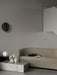 A beige Tearoom Sofa in a grey room, with a marble Plinth coffee table holding a TR Bulb Table Lamp and decorative objects.