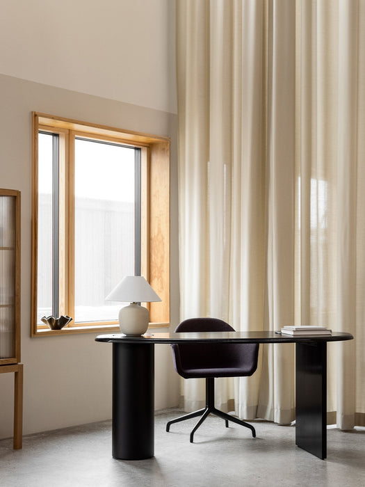 A black Eclipse Desk is paired with a Harbour Dining Chair and Torso Table Lamp in a naturally lit room with a large window.