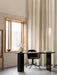 A black Eclipse Desk is paired with a Harbour Dining Chair and Torso Table Lamp in a naturally lit room with a large window.