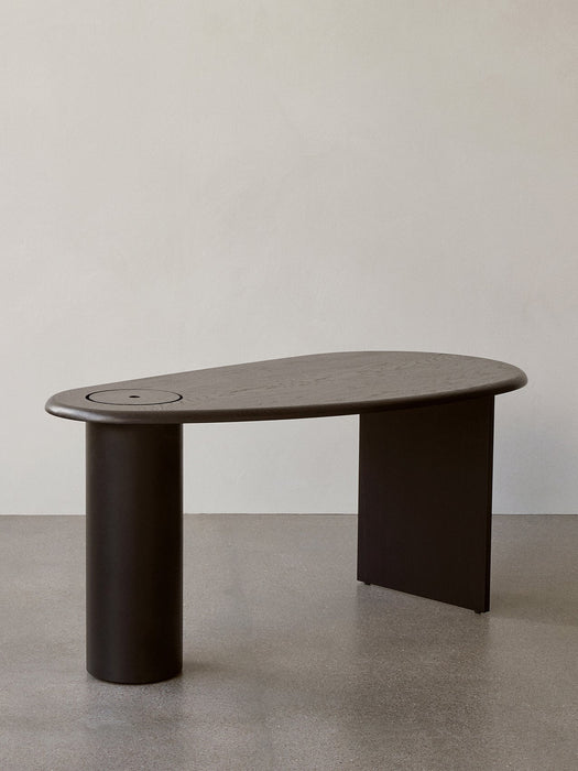 The Eclipse Desk in black lacquered oak, with a curved asymmetrical top, a cylindrical leg and a flat panel leg.