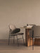Two upholstered Penguin Dining Chairs surround an Androgyne Dining Table with books and a Sentiment Paper Weight on top.