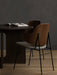 A Penguin Dining Chair with a walnut back and grey seat beside a dark wood Androgyne Dining Table with an open book.