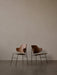 Two The Penguin Dining Chairs with sculpted walnut backrests and upholstered seats on thin black legs, set back-to-back.