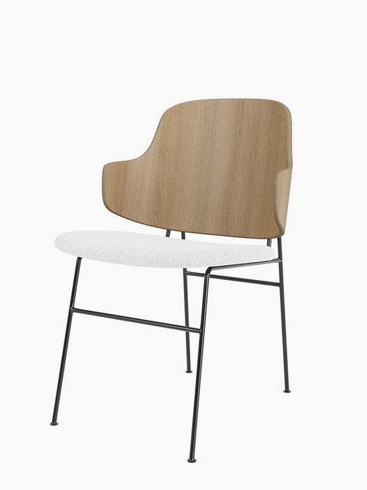 The Penguin Dining Chair, viewed from an angle, with a natural oak back, white textured seat, and thin black metal frame.