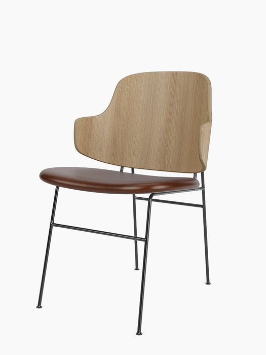 Angled view of The Penguin Dining Chair with a natural oak back, brown leather seat, and a slender black steel frame.