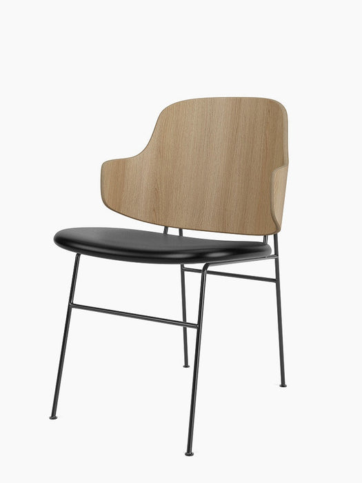 Angled view of The Penguin Dining Chair in natural oak with a black leather upholstered seat and a slender black metal frame.