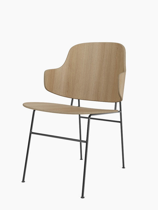 Angled view of the Penguin Dining Chair in natural oak, featuring a curved wooden back and seat on a slim, black metal frame.
