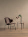 The brown upholstered Penguin Lounge Chair is next to a wooden Umanoff side table with a black Stance Vase and flowers.