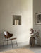 The Penguin Lounge Chair, with its dark wood seat and black frame, sits in a serene, minimalist room next to a large vase.
