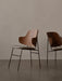 Two Penguin Lounge Chairs with iconic curved wooden backs and upholstered seats, set against a plain, neutral wall.