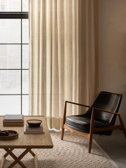 A tranquil living room featuring The Seal Lounge Chair, Jæger Lounge Table, and Gravel Rug in front of a large window.