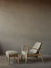 A side view of The Seal Lounge Chair and Seal Ottoman with natural oak frames and grey upholstery, on a dark wood floor.