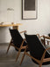 Rear view of two The Seal Lounge Chairs in walnut and black leather with an Eclipse Desk and Wing Table Lamp in background.