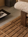 A close-up of a brown Tile Rug by a sheepskin Brasilia Lounge Chair with a Releve Platter and dark marble Plinth Tall.
