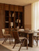 A dining room with an Androgyne Table, Ready Chairs, and Tile Rug. A bookcase holds a Nonna Lamp and Convergence Bookends.