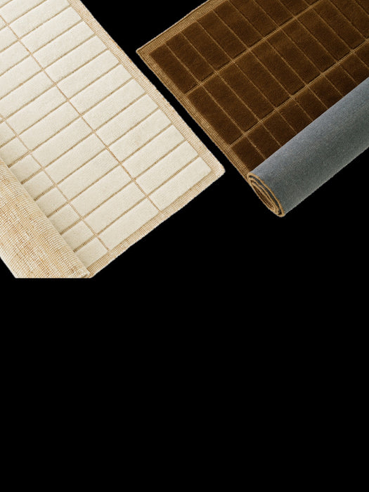 A cream rug and a brown rug, both with a tactile grid pattern. The rugs are rolled back, revealing their different backings.