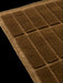 A close-up, detailed image of a brown woven textile with a geometric pattern of raised, plush rectangular sections.