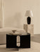 The Torso Table Lamp on a marble Plinth in a living room with an Eave Sofa and Androgyne Side Table.