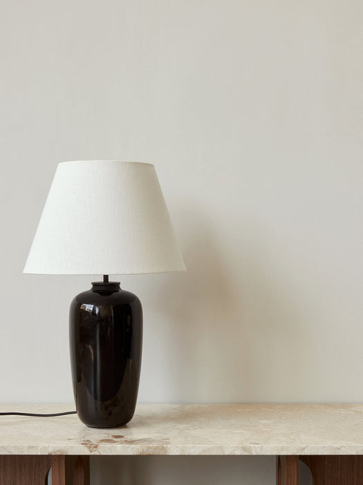 The Torso Table Lamp, 57, with its black glazed base and white linen shade, sits on a marble-topped Androgyne Side Table.