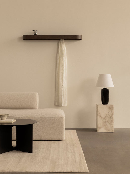 A calm room with an Eave Modular Sofa, Androgyne Side Table, Epoch Shelf, and Torso Table Lamp on a marble plinth.