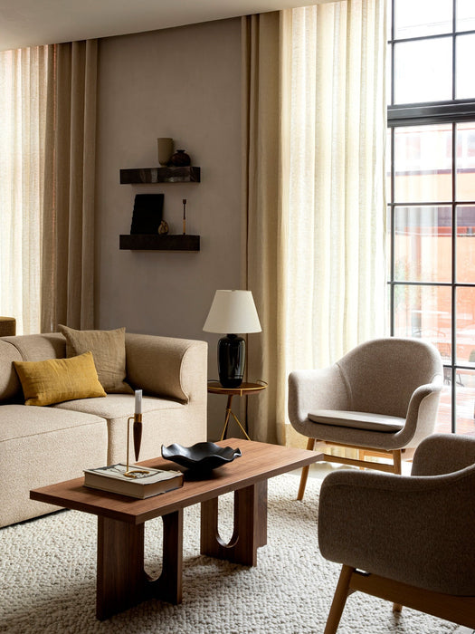 The Torso Table Lamp sits beside an Eave sofa in a living room with an Androgyn Lounge Table and Harbour Lounge Chairs.