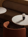 A Torso Portable Table Lamp on a marble Nook Dining Table, with a rust-coloured Tearoom Club Chair and a dark brown booth.