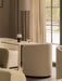 A portable Torso Table Lamp sits on a Nook Dining Table, placed between cream Tearoom Chairs in a cosy, softly lit interior.