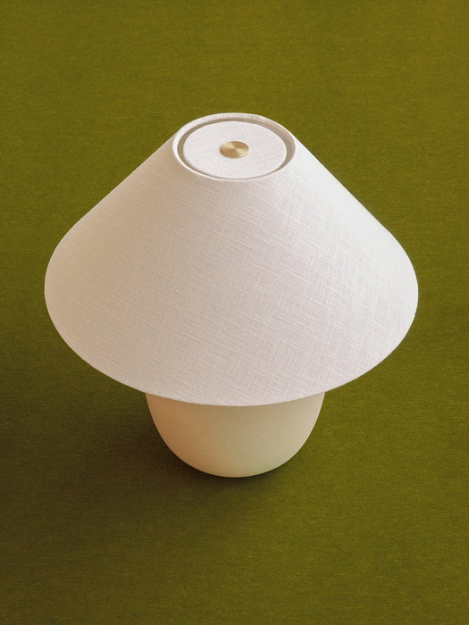 Overhead view of the Torso Table Lamp, 37. It has an off-white linen shade, brass dimmer, and rounded ceramic base.