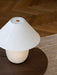 Close-up of the Torso Table Lamp, 37 showing the off-white linen shade and brass dimmer, placed on a dark wood table.