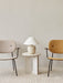 Torso Table Lamp on an Androgyne Side Table between a beige and a yellow Co Lounge Chair, set on a striped cream rug.