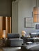 A modern living room featuring a grey Eave Sofa, with a beige Torso Table Lamp on a marble plinth and a Duca candelabra.