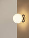 A close-up of the TR Bulb, Ceiling/Wall Lamp in polished steel, mounted in a corner, casting a warm glow on the walls.
