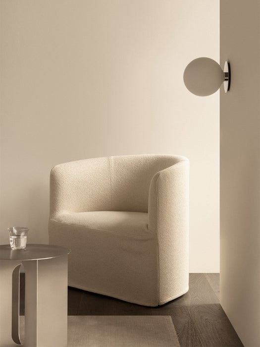 The TR Bulb Ceiling/Wall Lamp is mounted on a beige wall above a cream Tearoom Lounge Chair and an Androgyne Side Table.