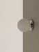 Close-up of the TR Bulb Ceiling/Wall Lamp in polished steel, its opal glass shade glowing against a two-toned wall.